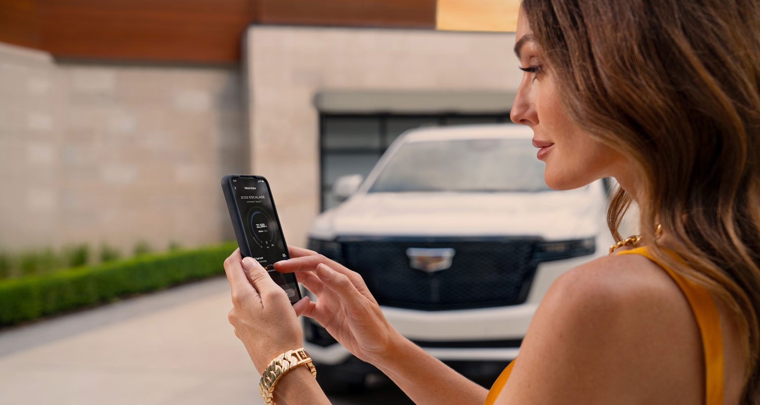 lady checking her mobile with a Cadillac vehicle background | Platinum Cadillac in Terrell TX