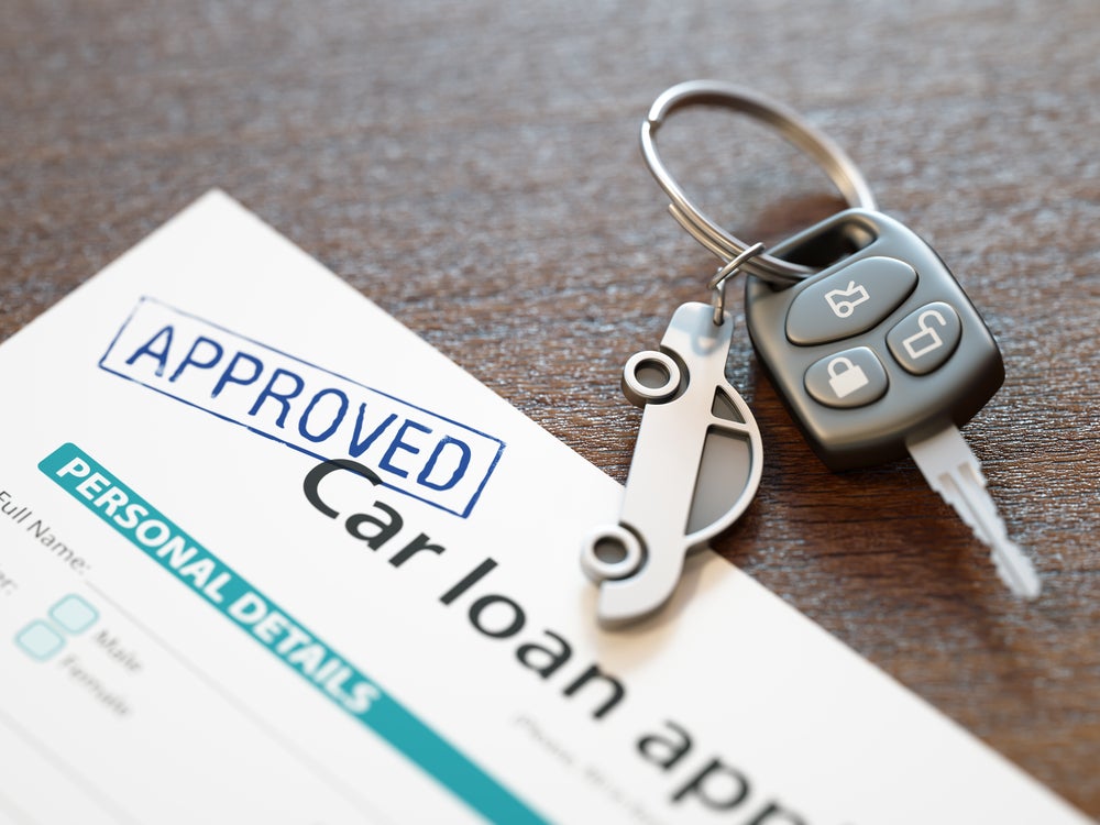 Approved car loan document with vehicle keys placed on a desk.
