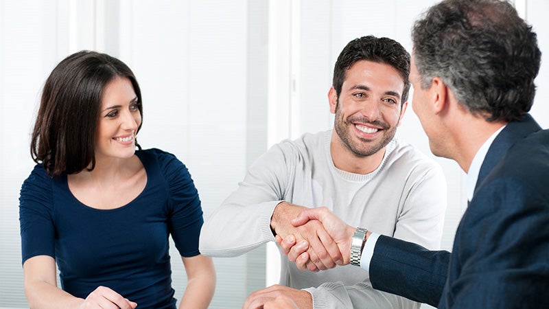Couple shaking hands with car dealer